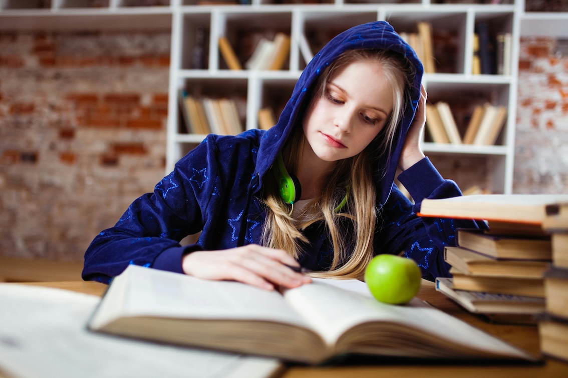 Joven estudiando de forma saludable con libros y una manzana, alternativa eficaz al metilfenidato para estudiar sin TDAH